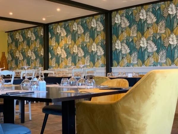 Salle sous verrière, papier peint à grandes feuilles, tables dressées
