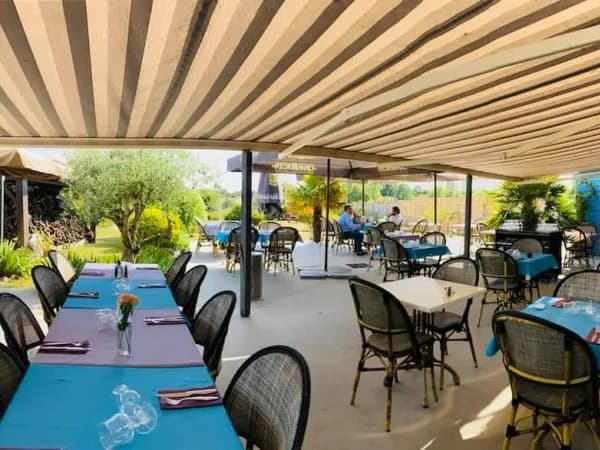 Terrasse couverte d'une pergola, chaises en rotin et nappes bleues
